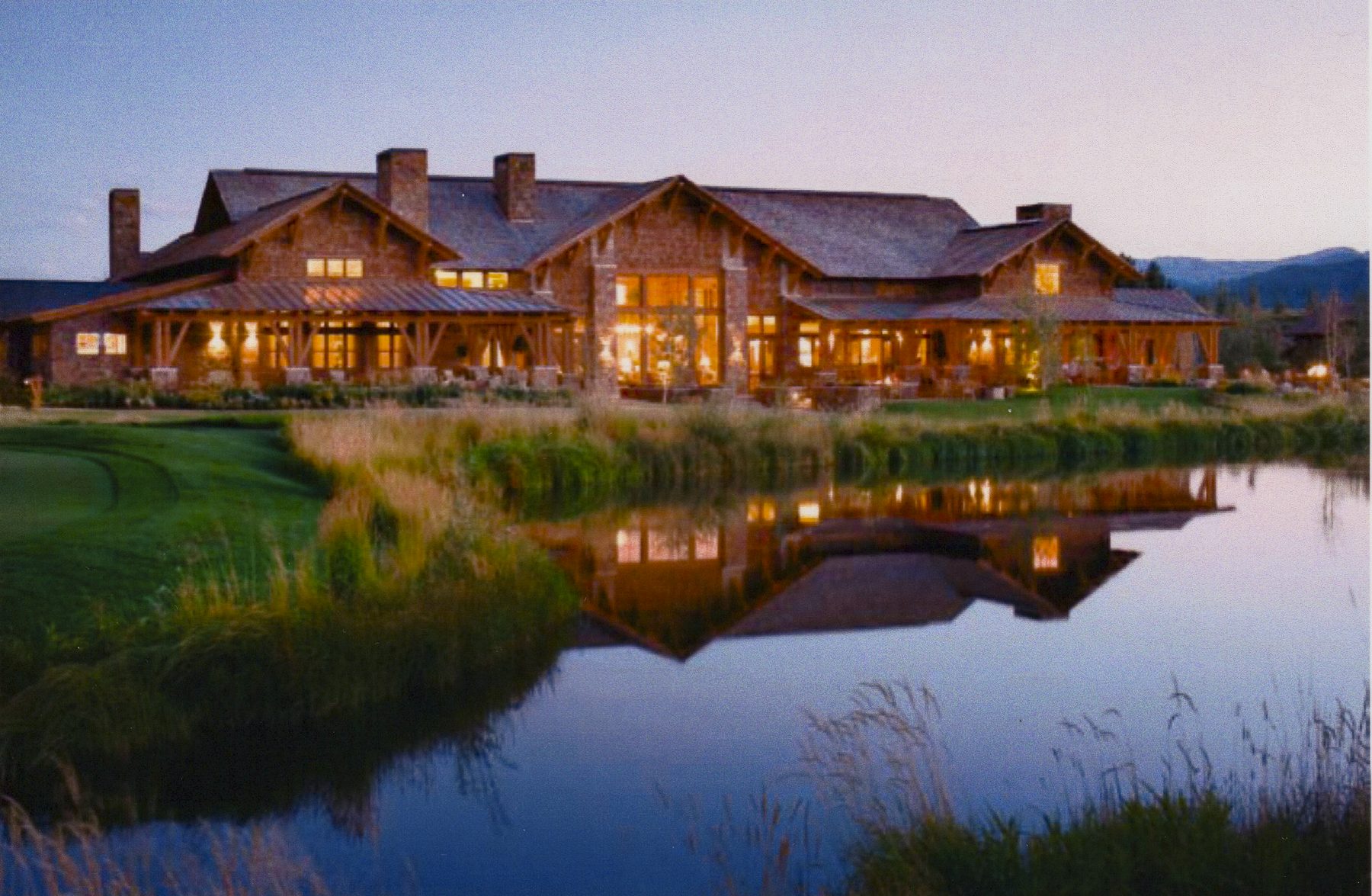 Timber lodge at dusk reflected in a pond, Jackson Hole