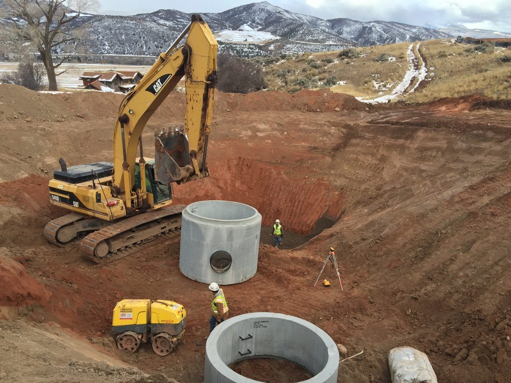 Excavation and utility installation with mountain backdrop
